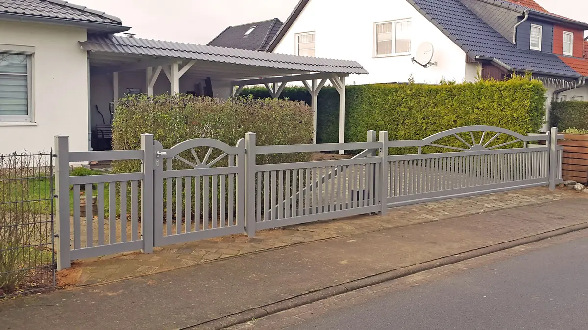 Hellgrauer Aluminiumzaun mit Fächerornament vor einem Carport